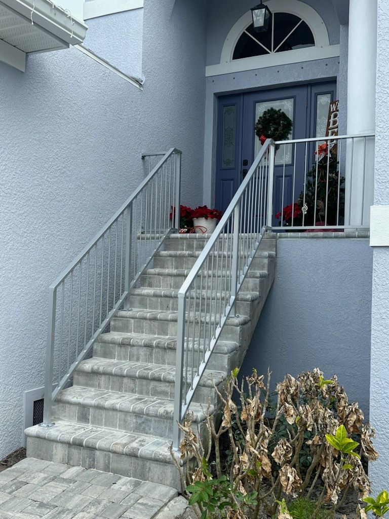 A set of stairs leading up to a blue door with a metal railing.