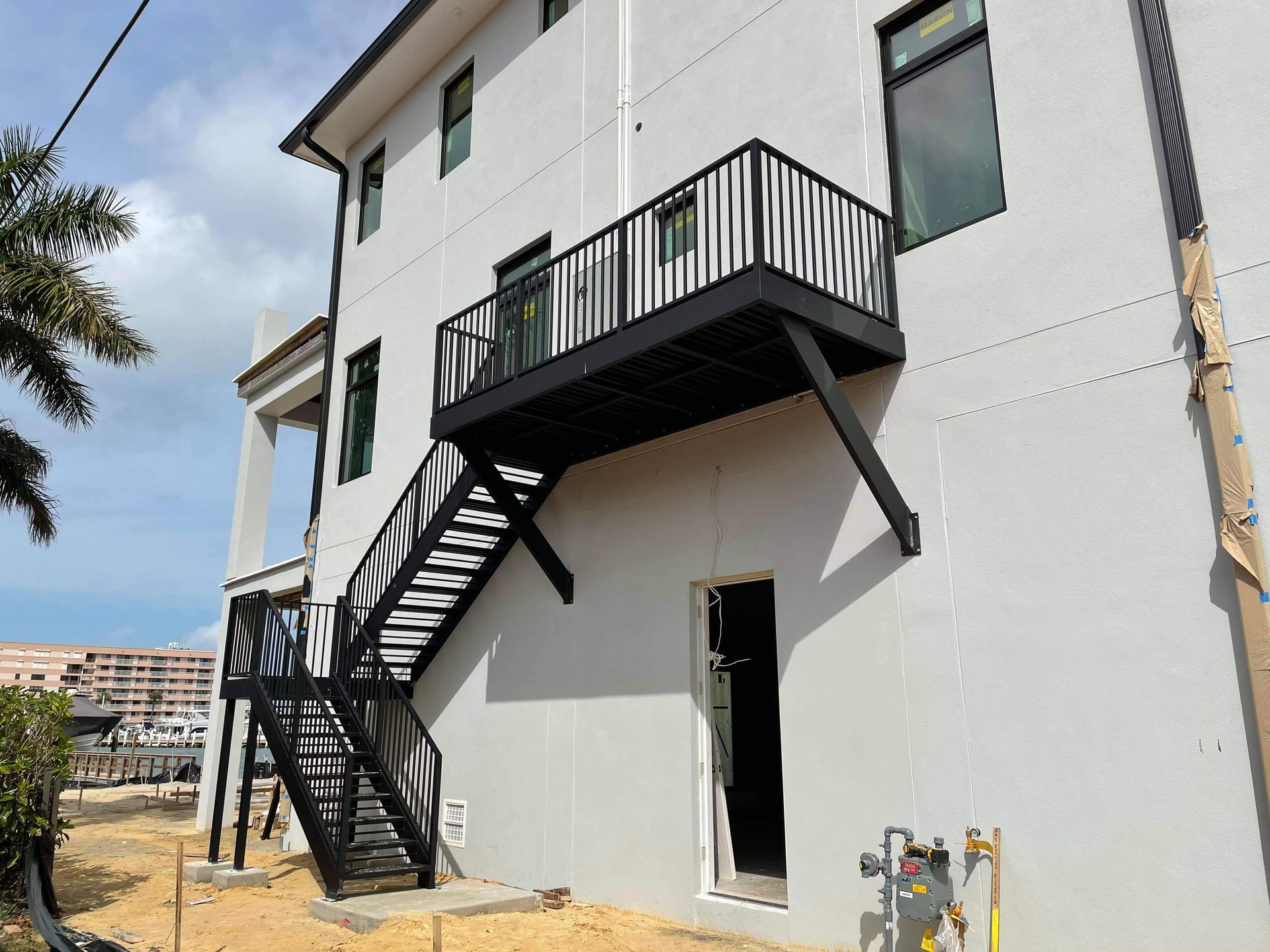 A white house with a black staircase on the side of it.