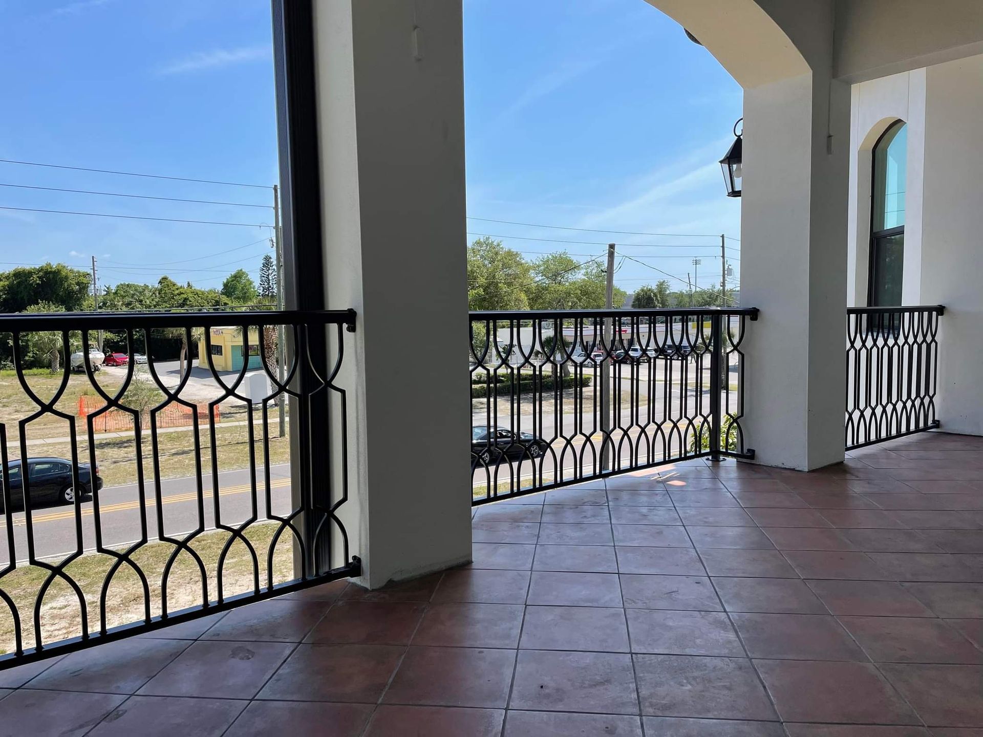 An empty balcony with a wrought iron railing and tile floor