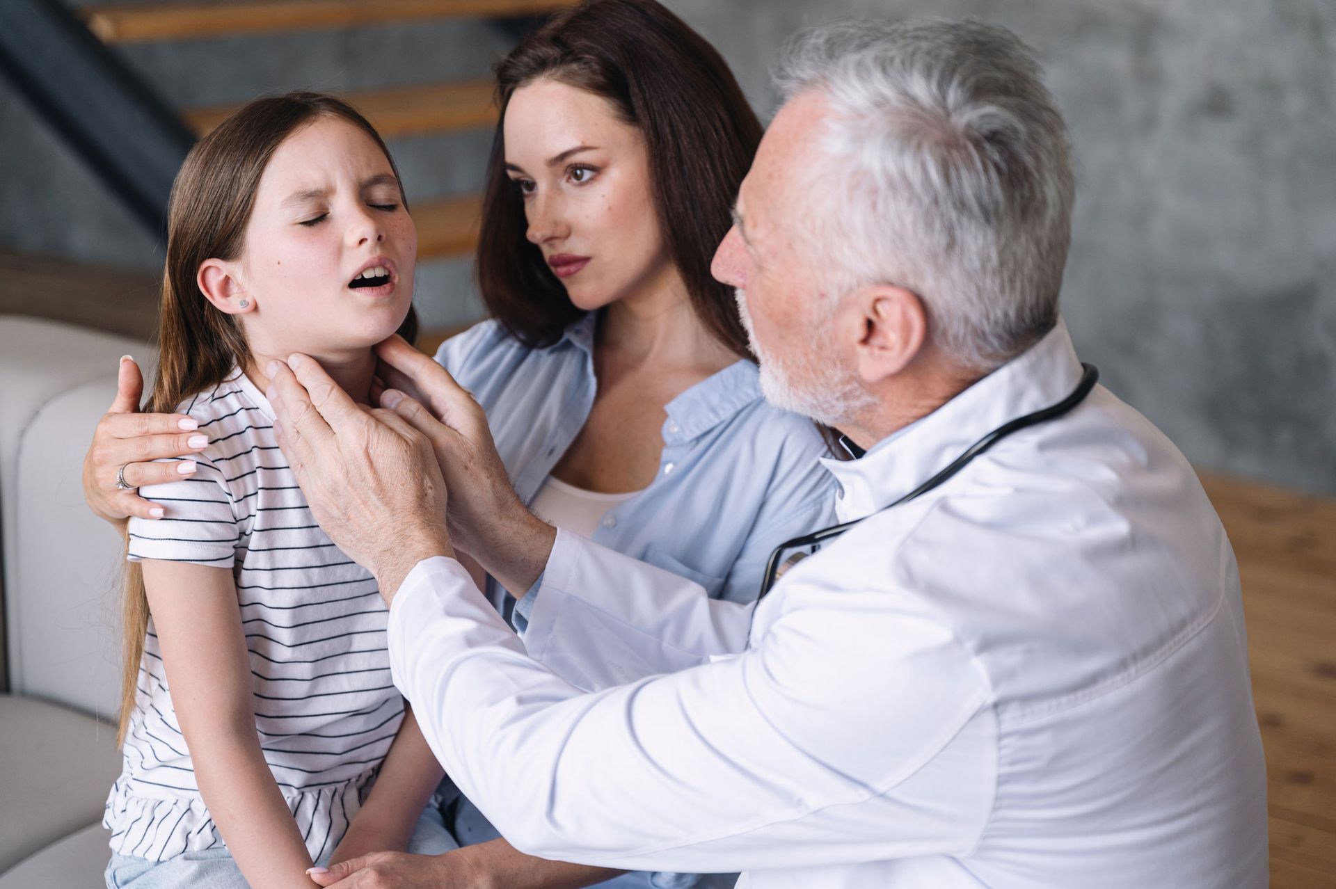 A small girl patient feels unwell, has a sore throat, and the doctor checks her lymph nodes