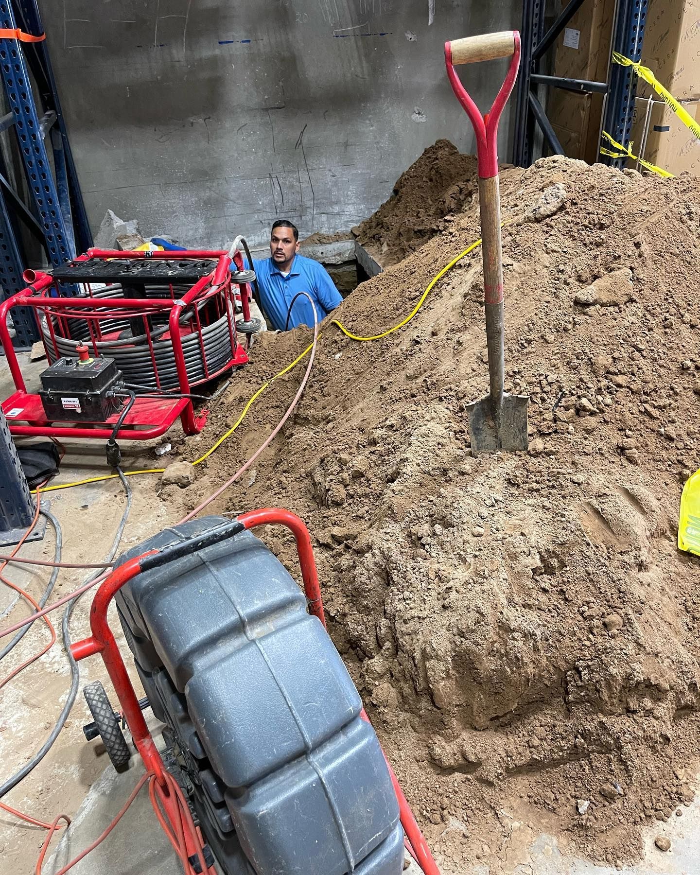 A man is standing in a pile of dirt next to a shovel.