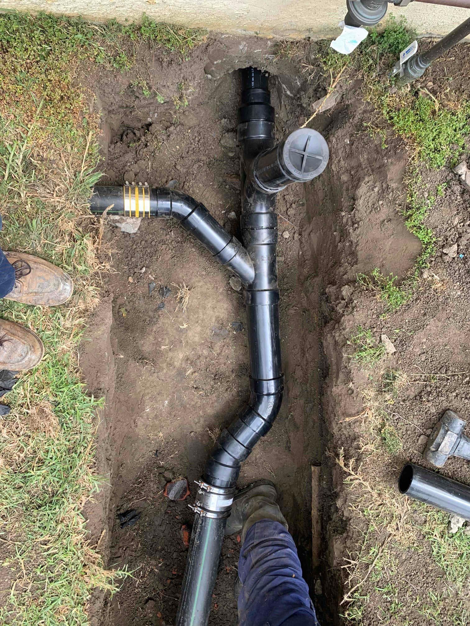 A person is standing next to a pipe in the dirt.