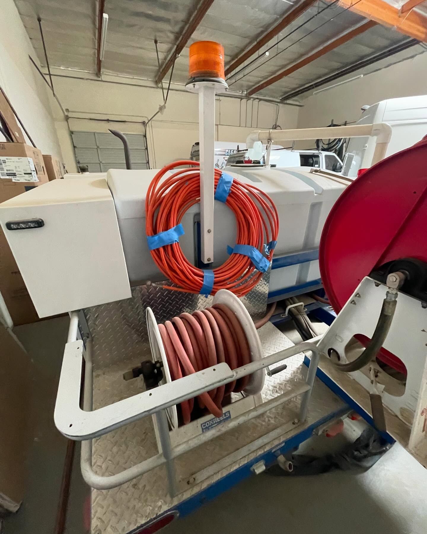 A hose reel with an orange hose attached to it in a warehouse.