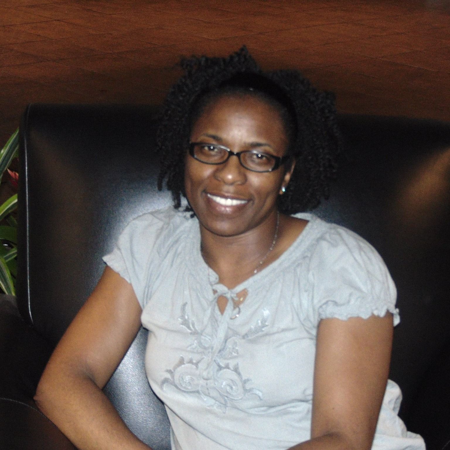 A woman wearing glasses and a grey shirt smiles for the camera