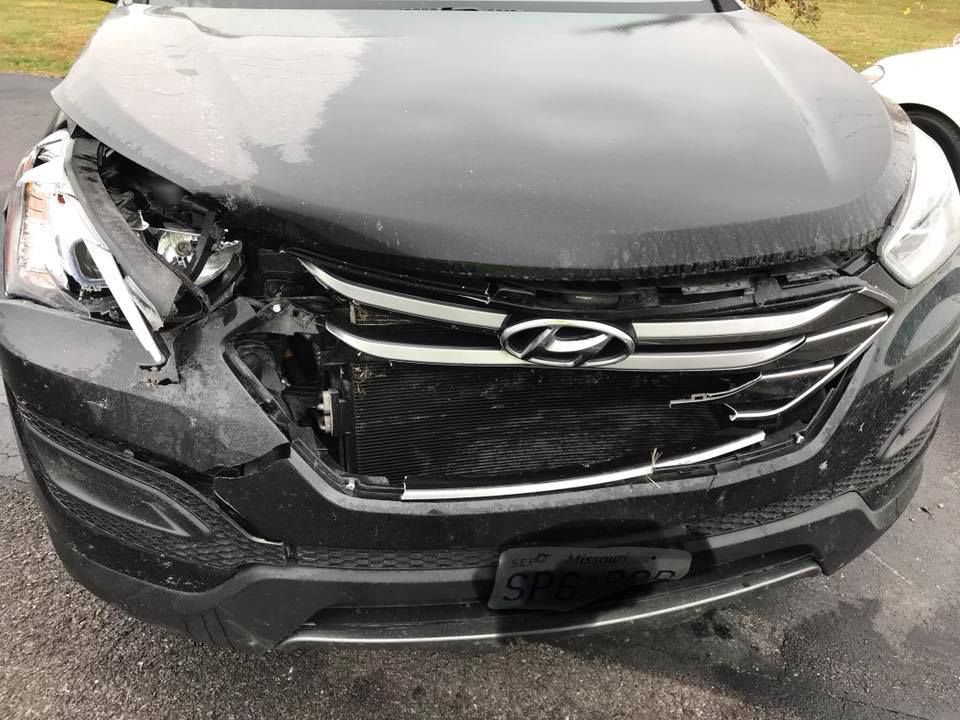 Damaged black Hyundai SUV; front end crushed, headlights broken.