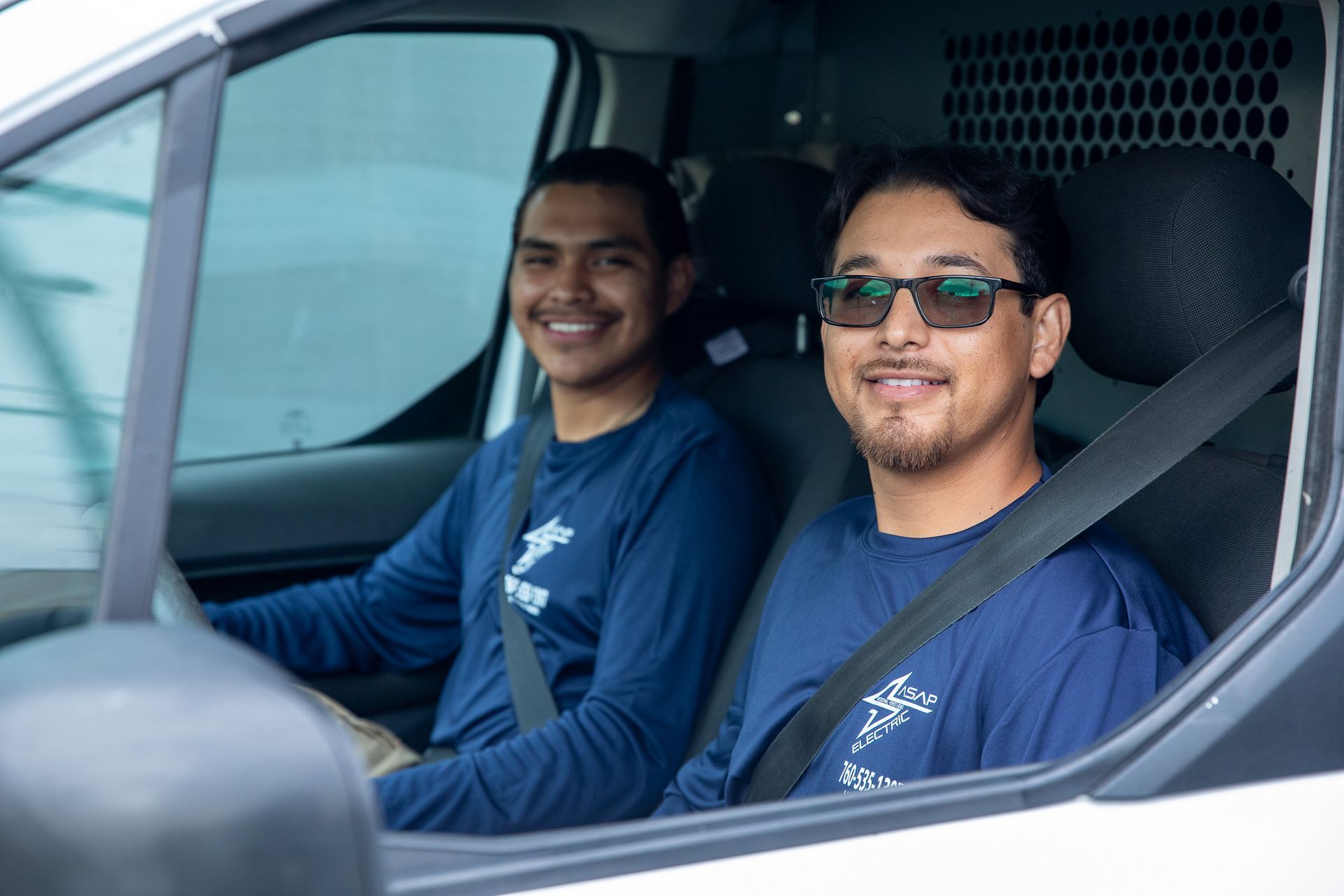 Electrician with yellow wires, standing in wooden frame of a house.