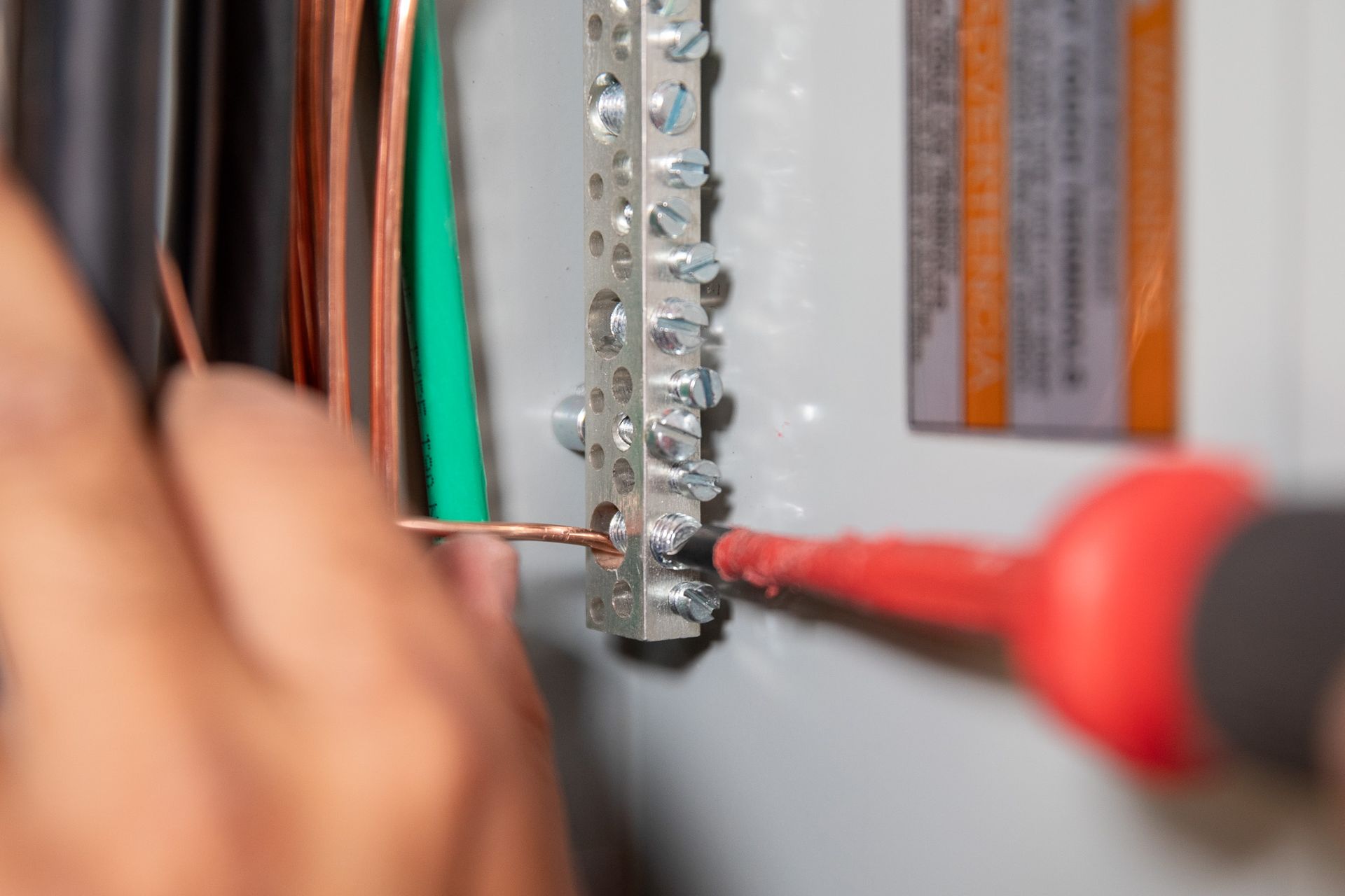 Person labeling electrical wires inside an electrical panel with a marker.