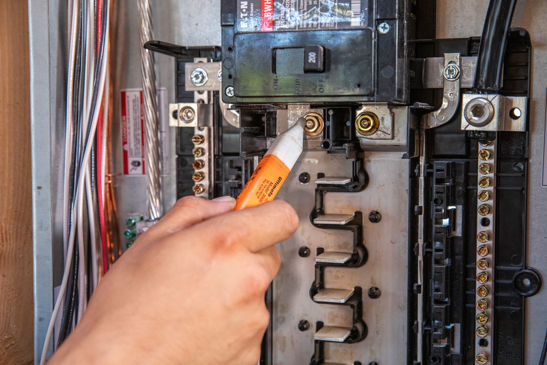 Electrician with yellow wires, standing in wooden frame of a house.