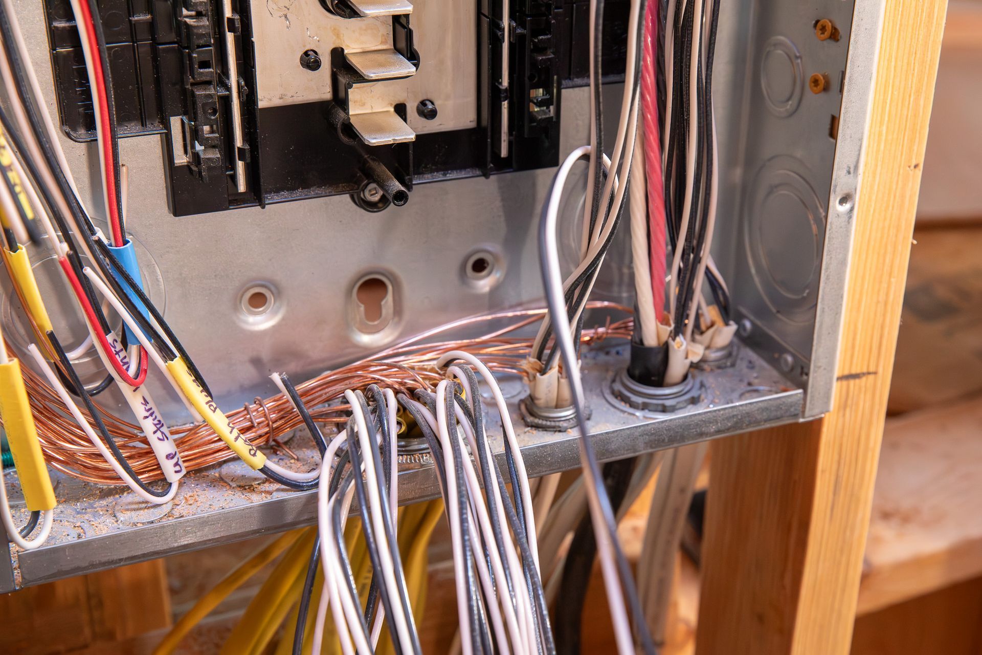 Person labeling electrical wires inside an electrical panel with a marker.