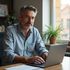 Man with graying hair using a laptop at a desk in a home office.