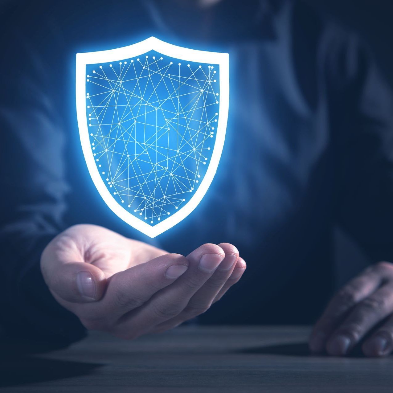 Person holding a glowing blue shield, representing cybersecurity and protection.