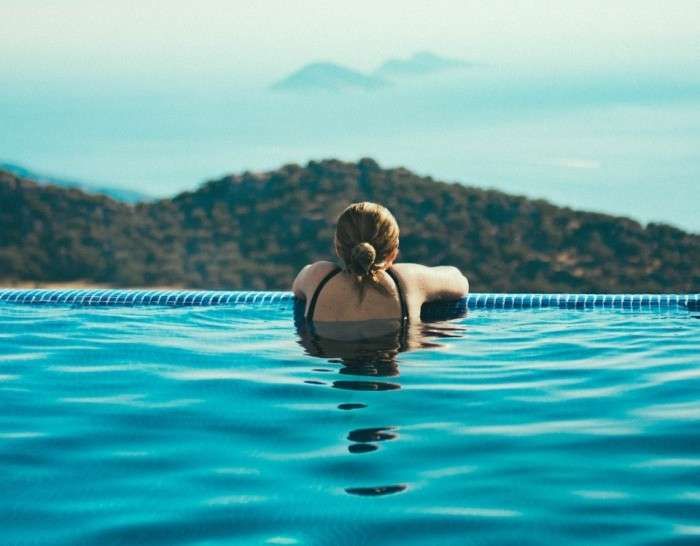 A Woman Is Swimming In An Infinity Pool With Mountains — Pool Concepts in Howard Springs, NT