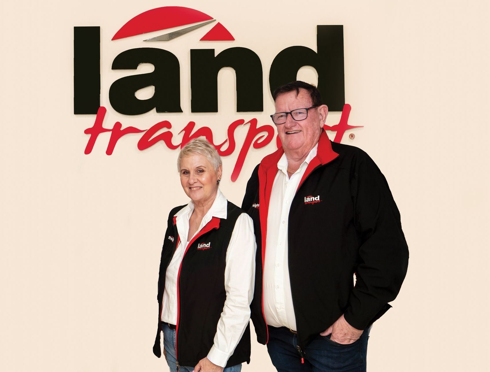 Barry and Raewyn Land, the owners of Land Transport proudly standing in front of the company's logo