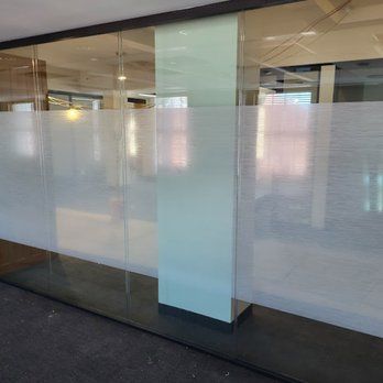 Office glass wall panels with a frosted, horizontal-striped privacy film and a central opaque column.
