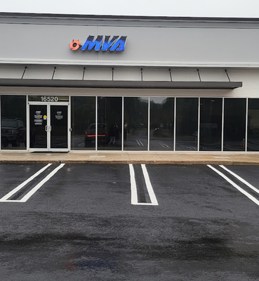 The MVA office exterior building front featuring blue signage, dark tinted windows, and a paved parking lot in front.
