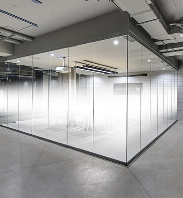 A conference room with glass walls, featuring a gradient privacy film, visible from a concrete-floored office space.