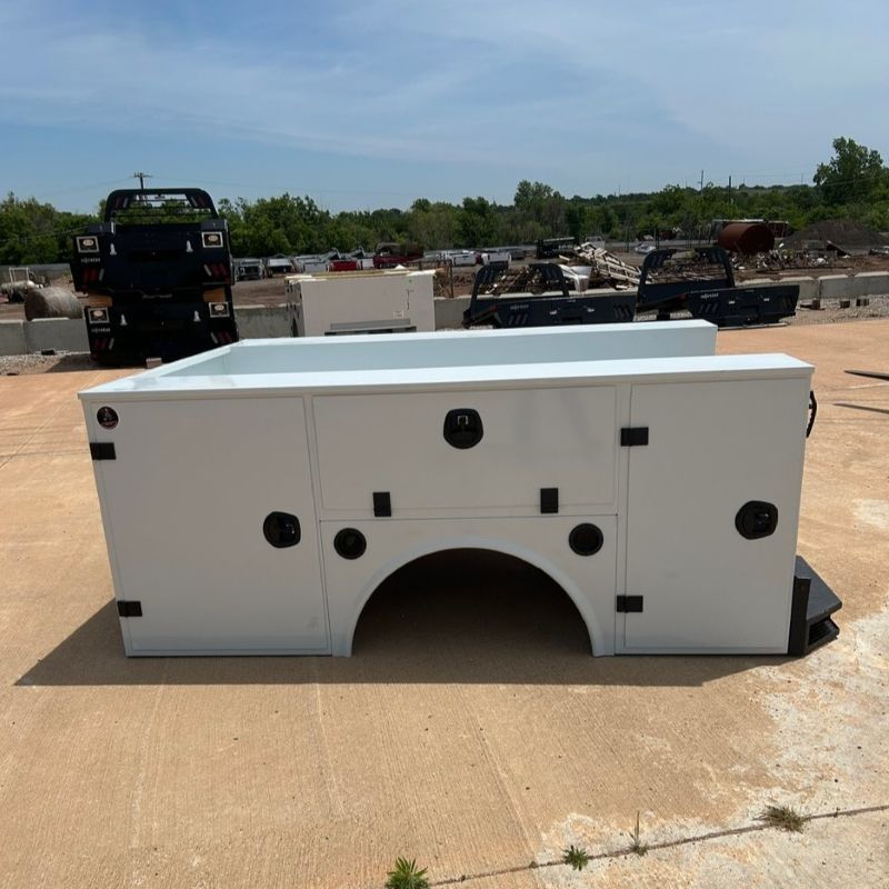 White utility truck bed body on a concrete lot under a clear sky.