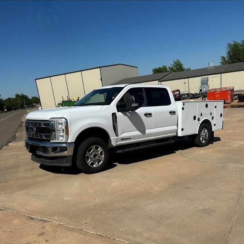 White utility truck parked on a sunny lot beside an industrial building