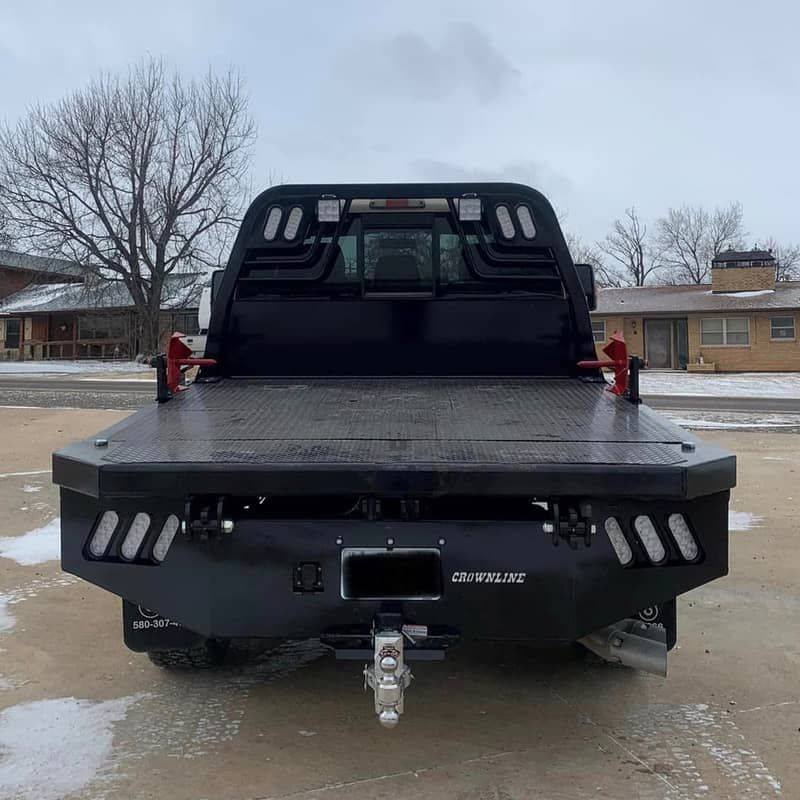 a black flatbed truck is parked in a parking lot
