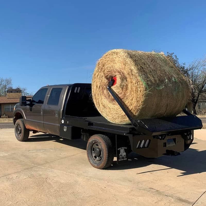 truck with arm bed lifting round bale of hay