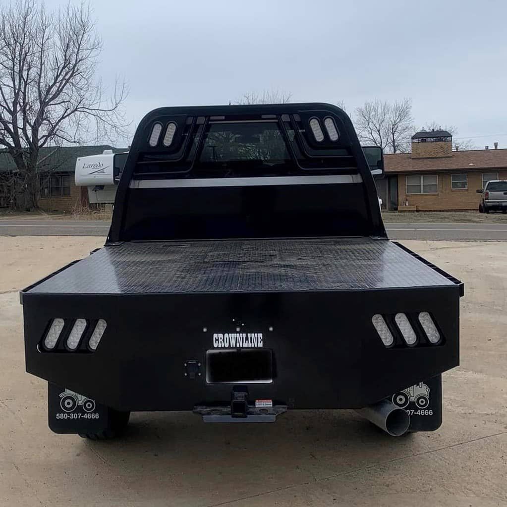 a black truck with a flat bed is parked in a parking lot .