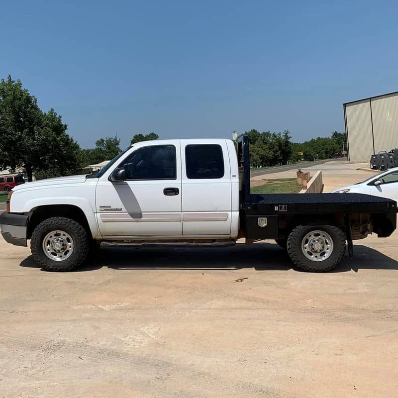 a white truck with a flat bed is parked in a parking lot .