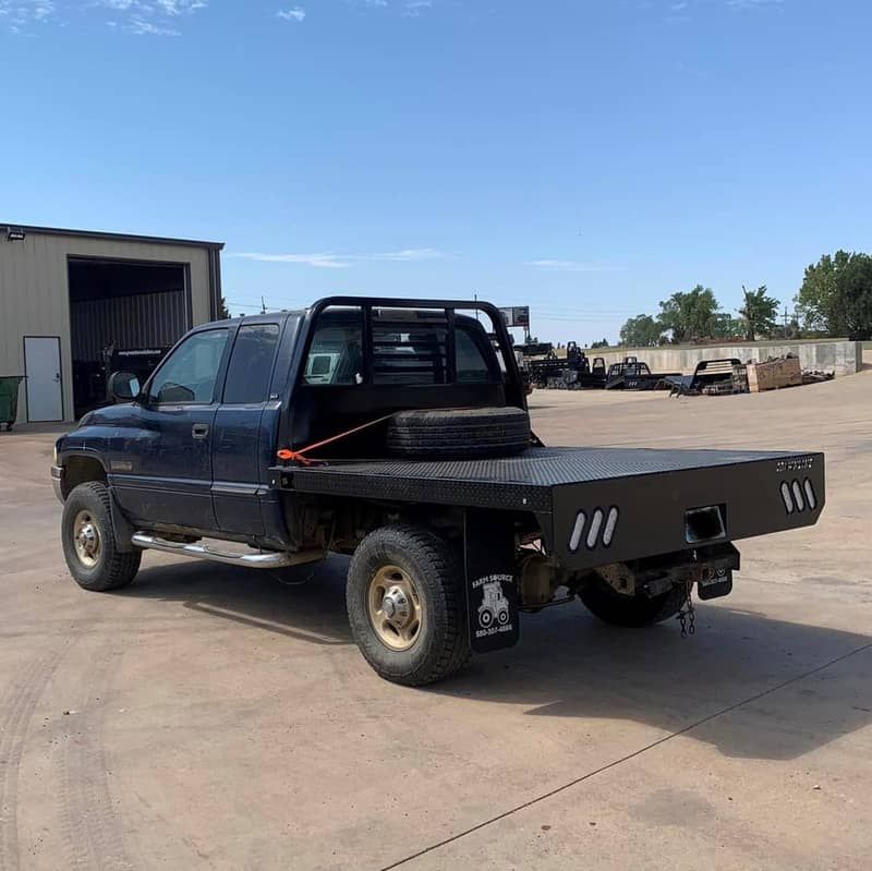 a black ram truck with a crownline flat bed is parked in a parking lot .