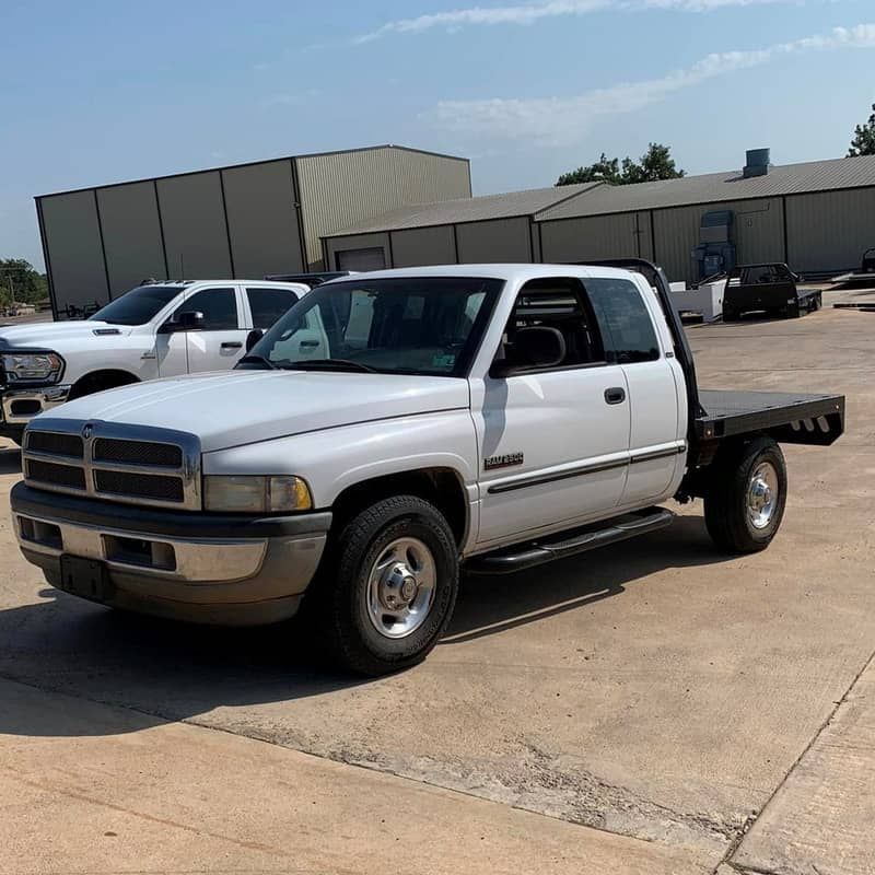 a white truck with a flat bed is parked in a parking lot