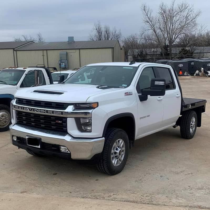 a white truck with a flat bed is parked in a parking lot .