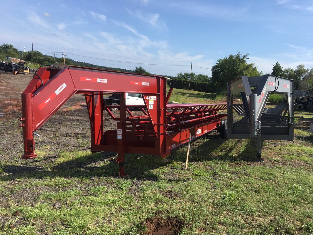 Photo of red Kodiak hay trailer that is long and made to haul round bales
