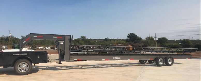 wide view of kodiak round bale trailer that i gray in color and is parked on gravel