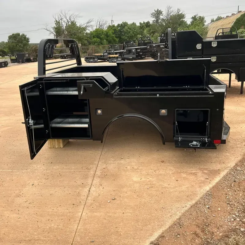 Black truck work bed with open side compartment and shelves parked on a concrete lot