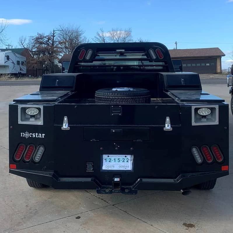 a black truck with norstar flatbed is parked in a parking lot with a texas license plate