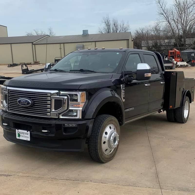 a black ford truck with norstar bed is parked in a parking lot .
