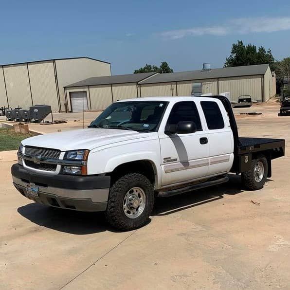 a white truck with a flatbed is parked in a parking lot .