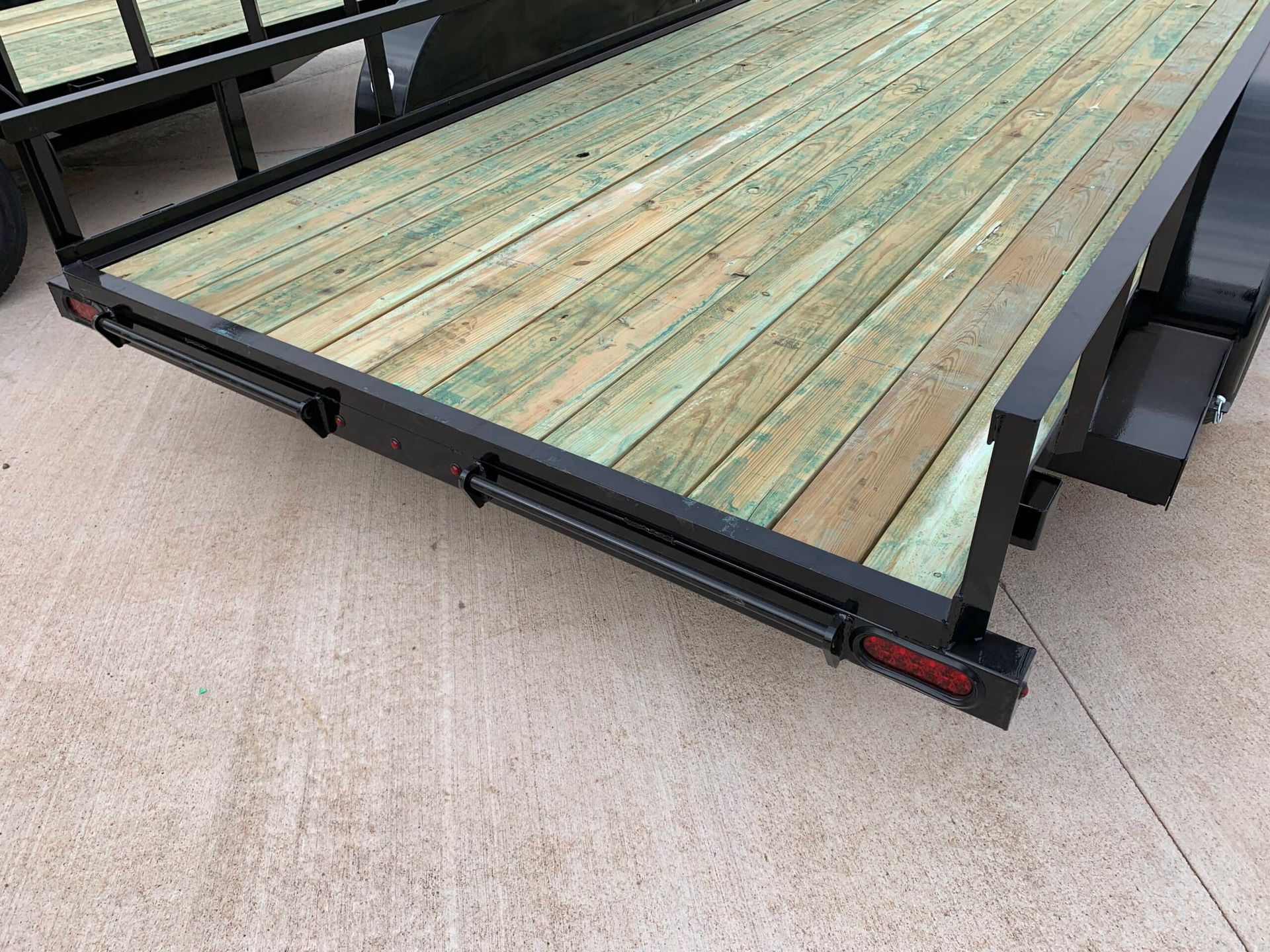 rear of black utility trailer with wood floor showing ramp connection
