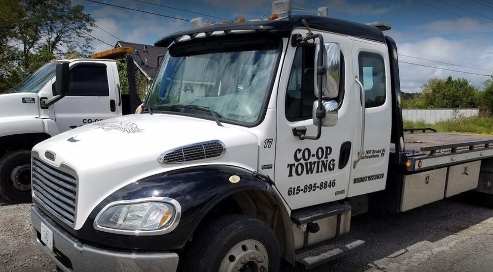 A white and black tow truck is parked on the side of the road.