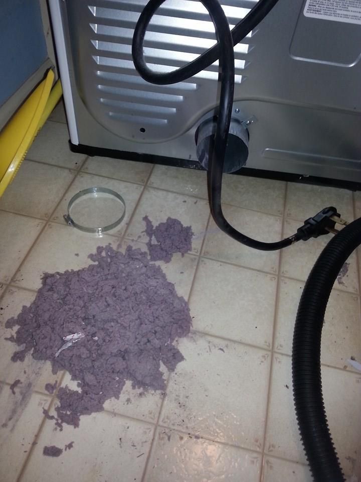 A dirty dryer is being cleaned with a vacuum cleaner
