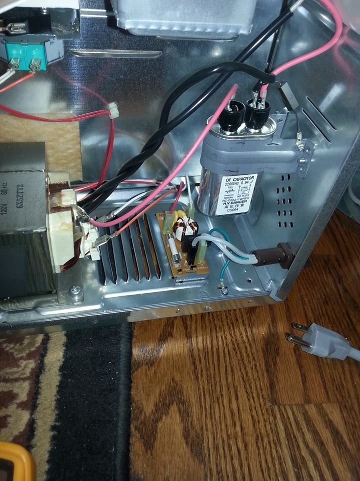 The inside of a microwave with a lot of wires coming out of it