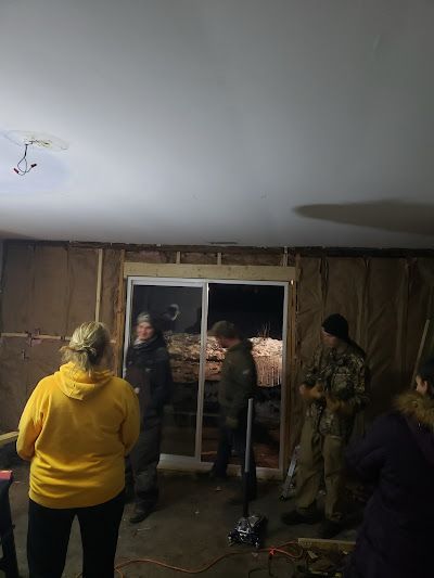 A group of people are standing in a room with a sliding glass door.