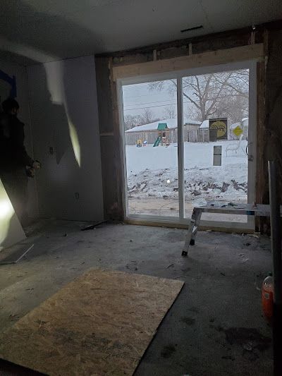 A room with a sliding glass door and a ladder in it.