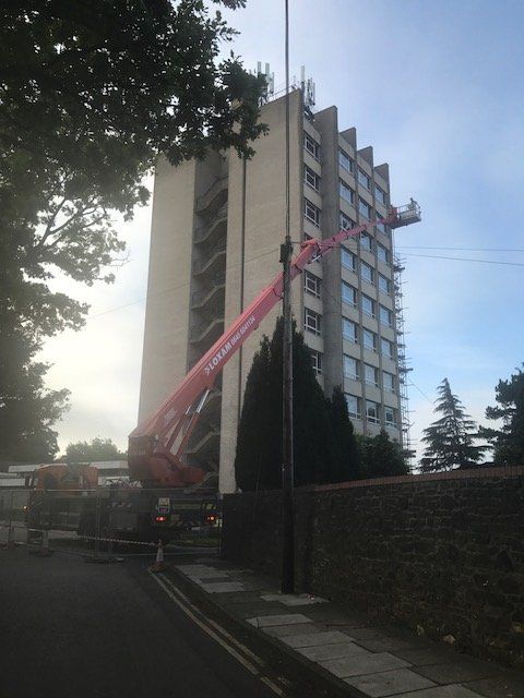 A crane reaching up the side of a large commercial building