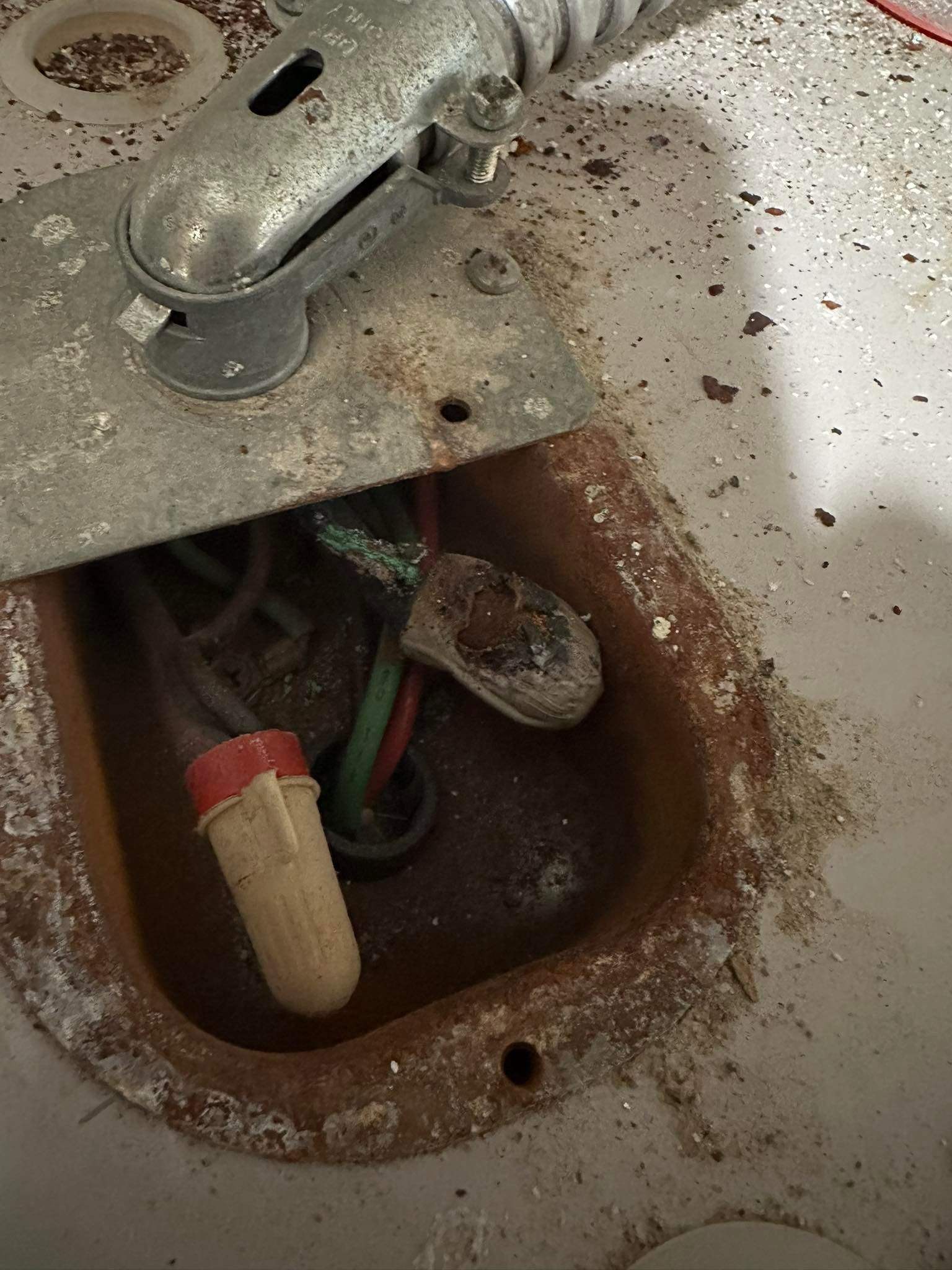 An open electrical junction box on a water heater showing corroded wiring and a wire nut.