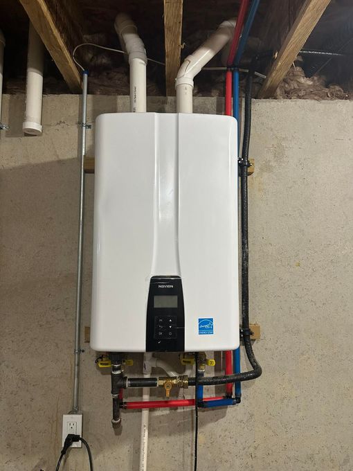 A gas furnace and water heater installed in a utility closet with the furnace access panel removed.