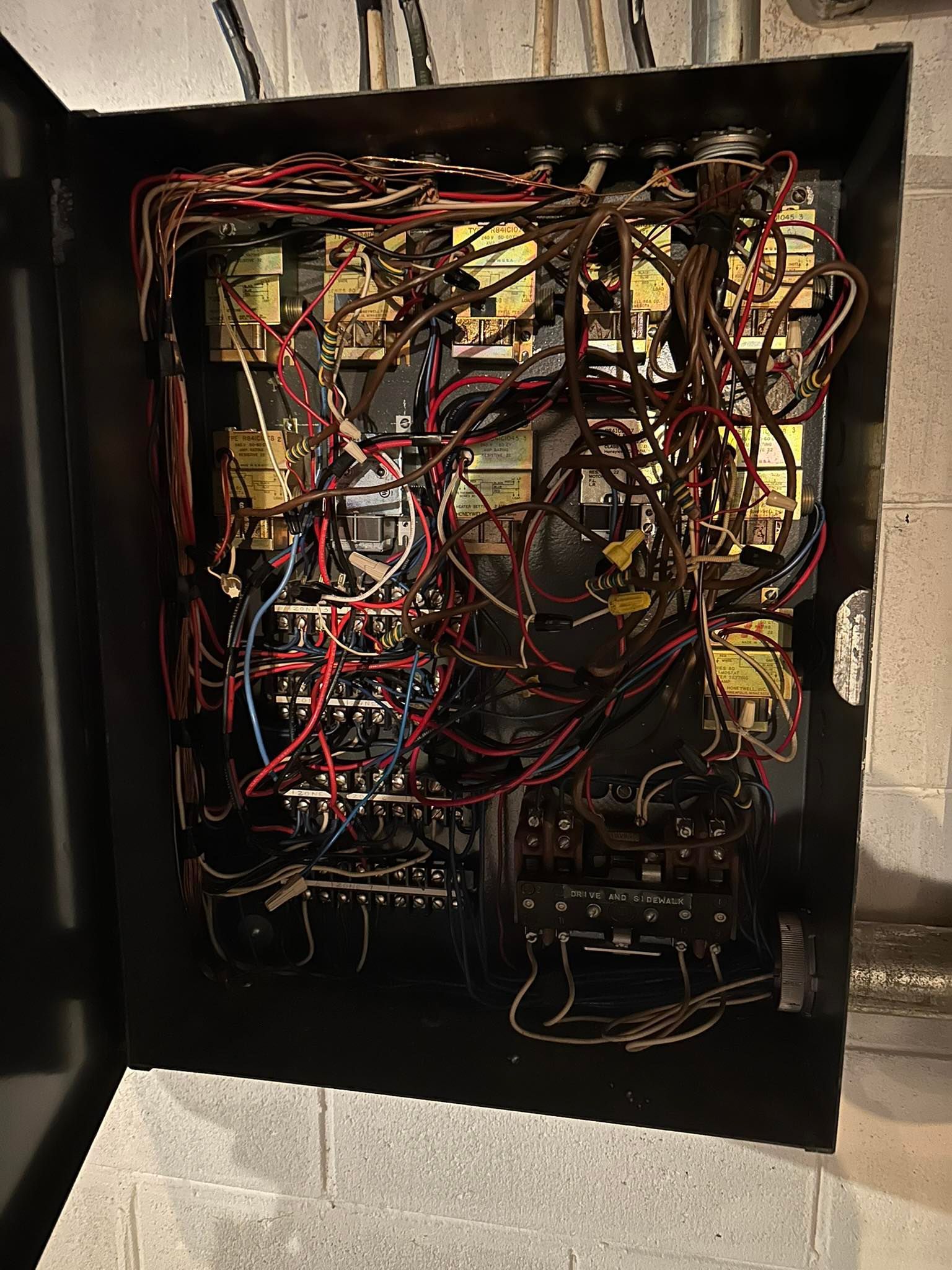 An open electrical control panel box filled with a complex, tangled web of numerous red and black wires.