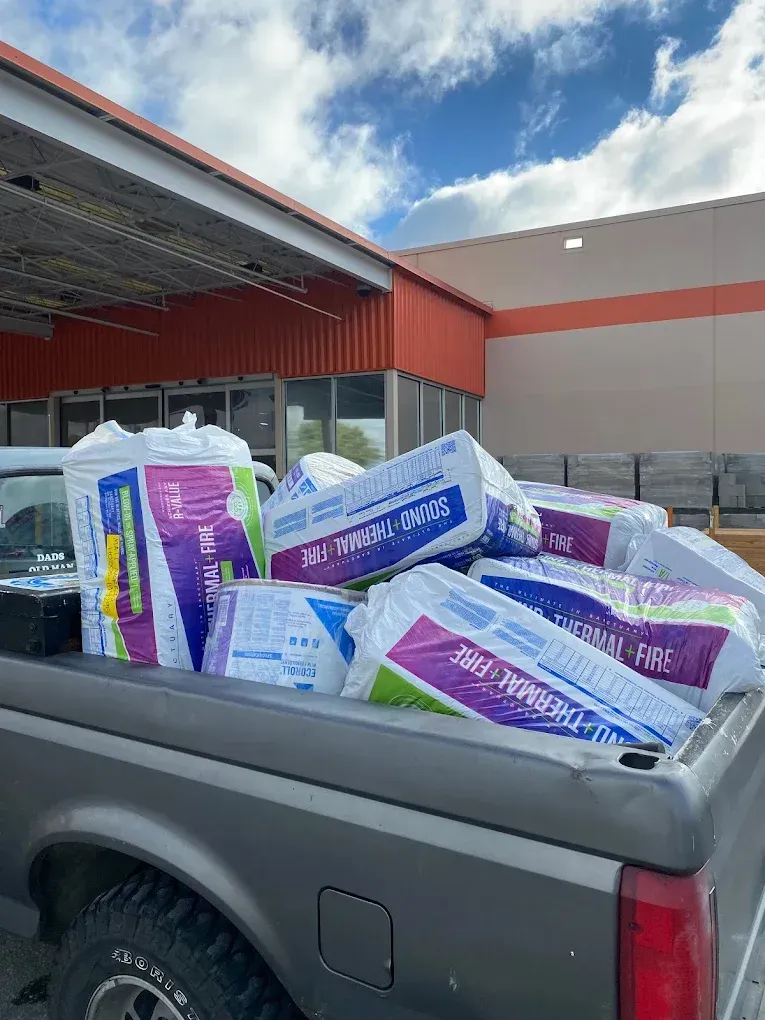 Truck bed filled with bags of insulation in front of a Home Depot store.