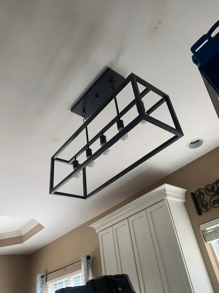 Black rectangular light fixture on a white ceiling above white cabinets.