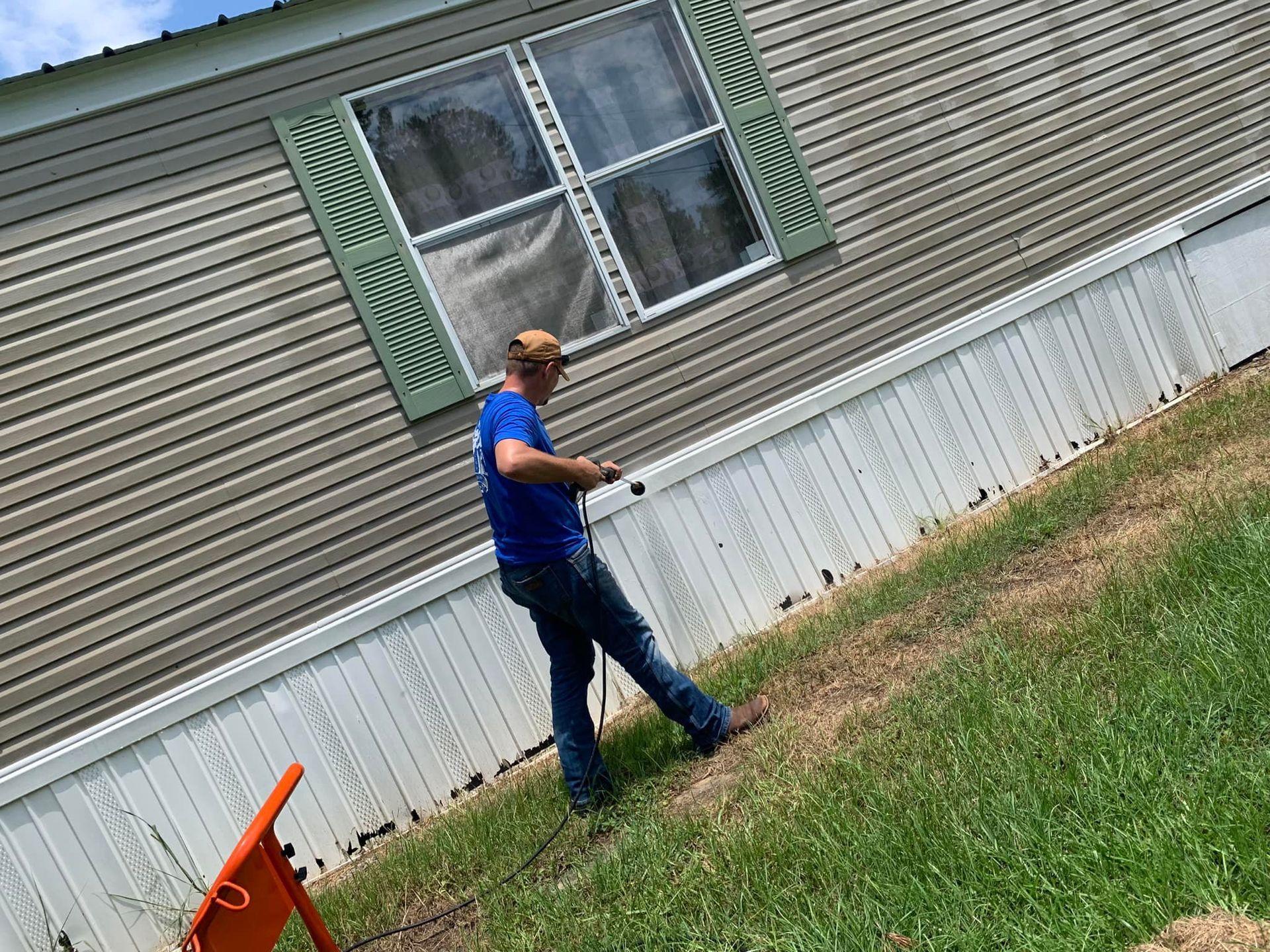 Man power washing a beige mobile home.