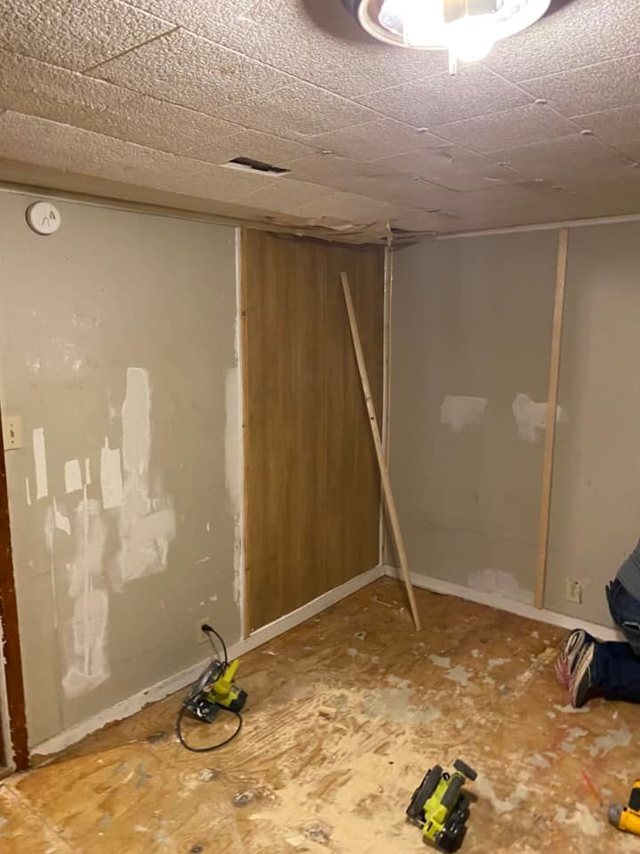 Renovating a room: Walls with wood paneling, drywall, tools on the floor.