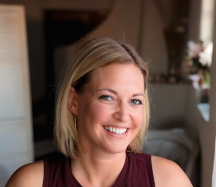A woman in a maroon tank top is smiling for the camera.